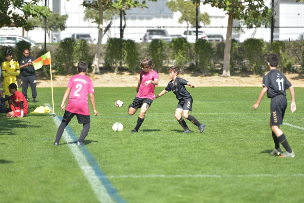 青いユニフォームのスポーツクラブチームの少年たちが芝生の上で円陣を組み、集客で成功したチームの団結力を象徴。
